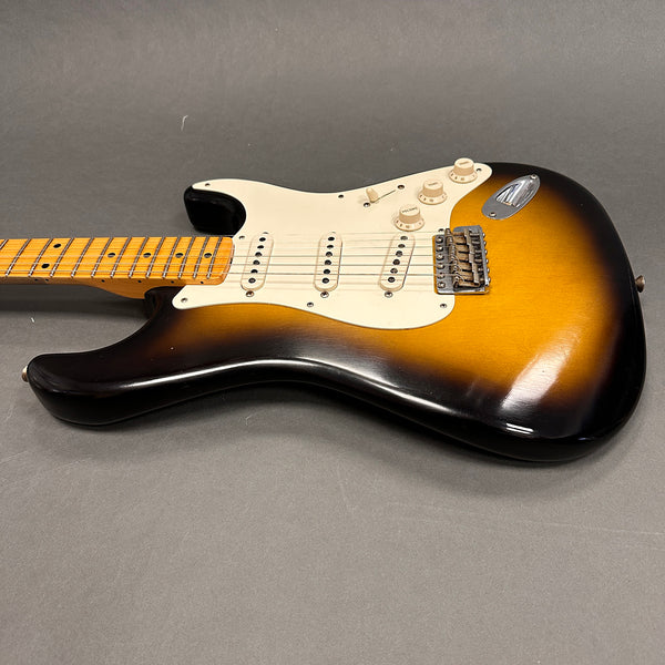Vintage sunburst electric guitar with maple fretboard, three single-coil pickups, and white pickguard on gray background