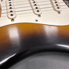 Close-up of vintage sunburst electric guitar body with white pickups and strings showing wear and finish cracks