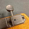 Close-up of vintage Grover tuning machine head on guitar with aged chrome finish and textured golden wood background
