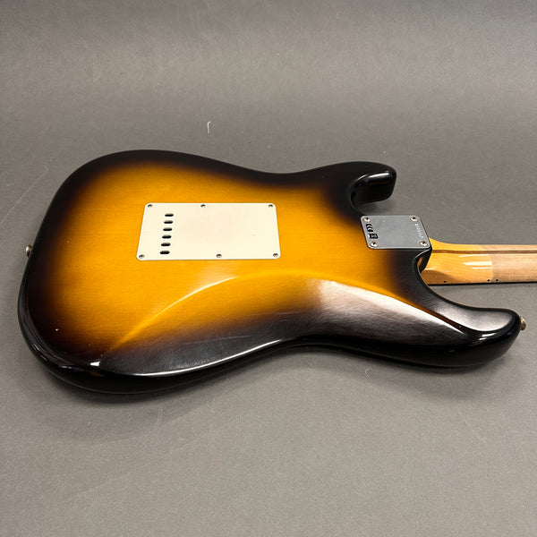 Sunburst finish electric guitar body with white backplate and maple neck heel plate on gray background