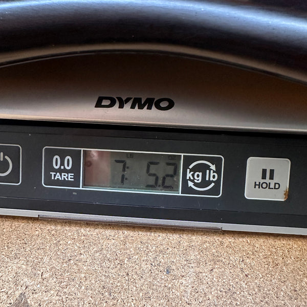 Close-up of Dymo digital scale display showing guitar weight of 7 pounds 5.2 ounces at Coffee House Guitars.