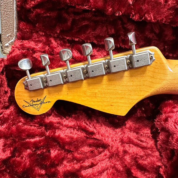 Close-up of vintage Fender Custom Shop guitar headstock with six tuning pegs on plush red guitar case interior
