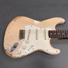 Close-up of vintage-style cream electric guitar body with three single-coil pickups, white pickguard, and worn finish showing wood grain and aging effects on gray background
