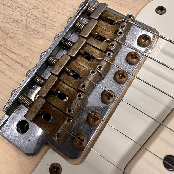 Close-up of vintage Fender electric guitar bridge and rusty saddles with strings on cream cracked finish body