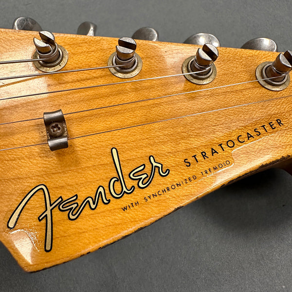 Close-up of vintage Fender Stratocaster guitar headstock with weathered wood finish and tuning pegs