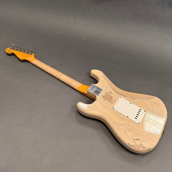 Vintage worn electric guitar back view showing natural wood finish and metal neck plate on gray background