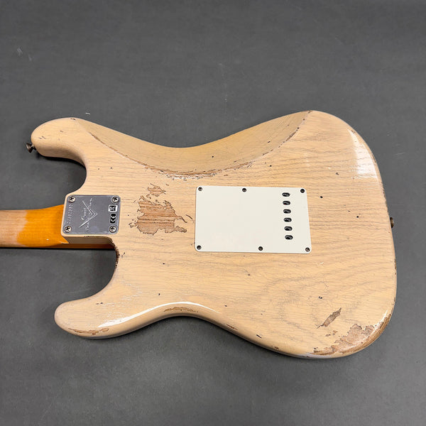 Vintage worn beige electric guitar back with visible wood grain and cracked finish, showing signs of heavy use and aging, featuring a metal neck plate and white plastic cavity cover.