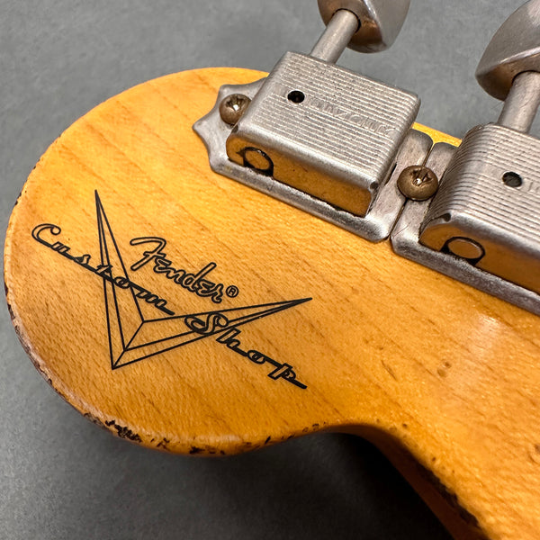 Close-up of vintage Fender Custom Shop guitar headstock with tuning pegs and logo on wood grain finish