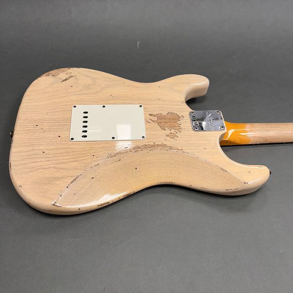 Back of vintage cream electric guitar with worn finish and white plastic backplate on gray background