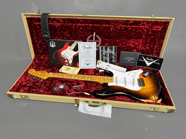Fender Custom Shop 1957 Stratocaster relic electric guitar in sunburst finish with maple neck and fretboard, displayed inside a vintage tweed hard case with red plush lining, including Fender certificate of authenticity, accessories, and guitar strap.