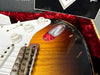 Close-up of sunburst electric guitar body showing volume and tone knobs, white pickguard, vintage bridge, and jack plate with visible wear and paint chips.