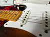 Close-up of vintage Fender Stratocaster electric guitar body and maple neck with single-coil pickups and white pickguard