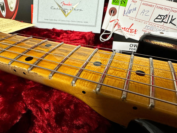Close-up of vintage Fender electric guitar maple neck and frets with Fender certificate and setup tags on red plush case interior