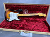 Fender Stratocaster electric guitar with sunburst finish and maple neck resting in a vintage tweed hard case with red velvet interior marked "Stratocaster 60" edition