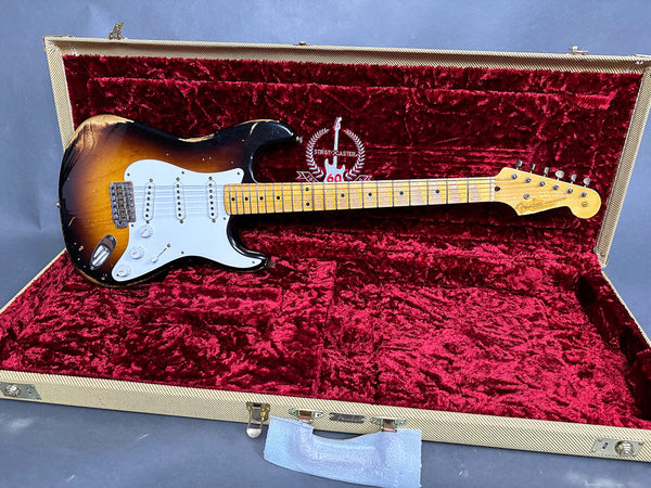 Fender Stratocaster electric guitar with sunburst finish and maple neck resting in a vintage tweed hard case with red velvet interior marked "Stratocaster 60" edition