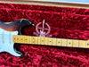 Close-up of Fender Stratocaster electric guitar neck and body with wear marks, lying in red plush case with 60 years Stratocaster embroidery