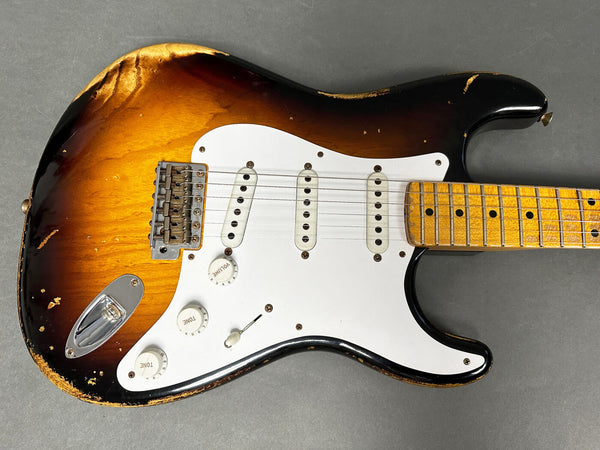 Vintage sunburst electric guitar with white pickguard and maple neck showing worn and chipped finish on body edges