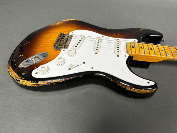 Vintage sunburst electric guitar with white pickguard and three single-coil pickups, showing worn and chipped edges on body and maple neck with dot inlays