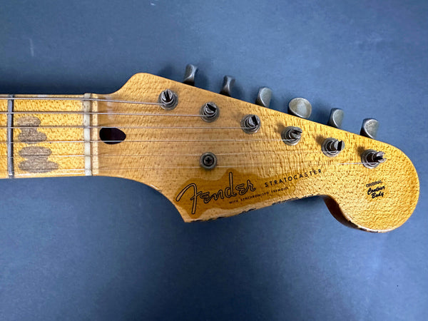 Close-up of vintage Fender Stratocaster guitar headstock with six tuning pegs and worn wood finish
