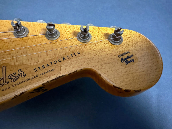 Close-up of vintage Fender Stratocaster guitar headstock with synchronized tremolo and original contour body logo on blue background