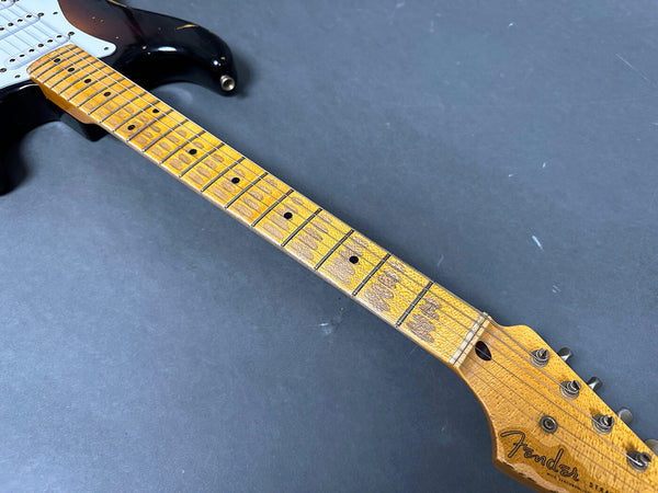 Close-up of Fender Stratocaster electric guitar neck and headstock with worn maple fretboard and vintage tuners on gray background