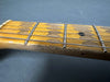 Close-up of worn vintage guitar maple neck and fretboard with metal frets and steel strings on gray background
