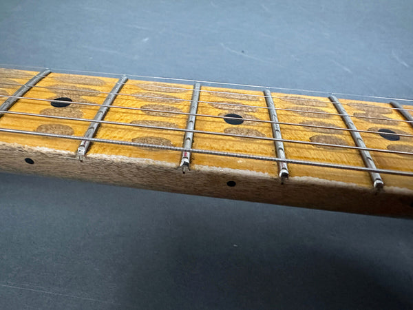 Close-up of worn maple guitar fretboard with metal frets and black dot inlays, vintage electric guitar neck detail