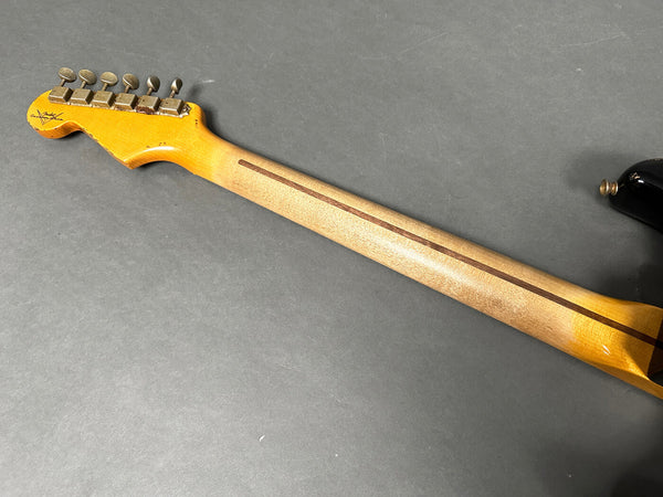Vintage Fender electric guitar maple neck with worn finish and tuning pegs viewed from the back on gray background
