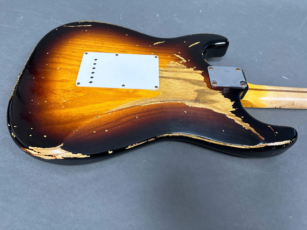 Back view of vintage sunburst electric guitar body showing worn and chipped finish with visible wood grain and metal neck plate on gray background