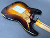 Vintage sunburst electric guitar body with heavy paint wear and relic finish on gray background, showing back side and neck heel plate
