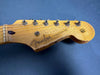 Close-up of vintage Fender Stratocaster guitar headstock with tuning pegs and worn maple neck on blue background