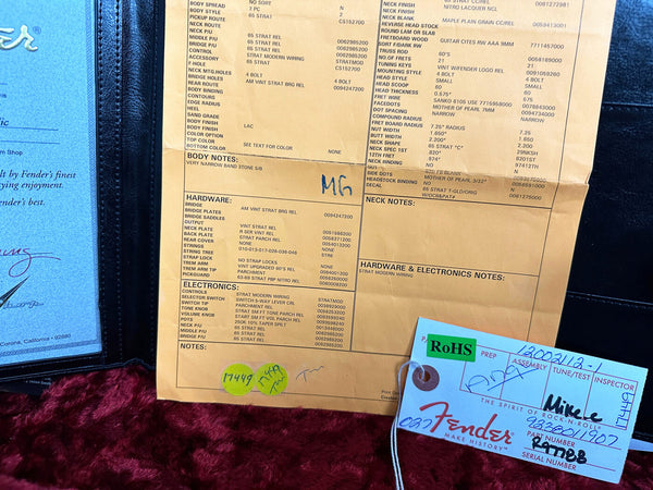 Fender Custom Shop detailed specification sheet for 65 Stratocaster guitar, including body style, pickup routing, hardware, electronics, and neck notes, alongside Fender production tag with part number 9823201907 and RoHS compliance sticker