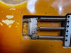Close-up view of vintage electric guitar tremolo cavity showing three tension springs and metal claw on a sunburst finish guitar body with wear and paint chips