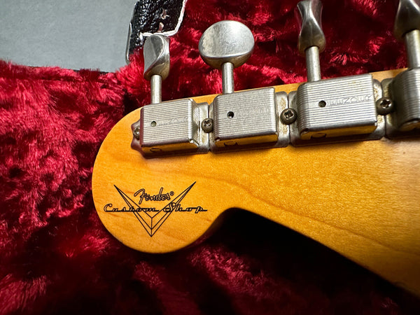 Close-up of Fender Custom Shop guitar headstock with vintage tuning machines on red plush guitar case lining
