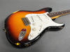 Electric guitar with sunburst finish and white pickguard showing vintage wear and scratches on body edges, close-up angle
