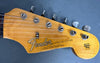 Close-up of Fender Stratocaster guitar headstock with tuning pegs and original contour body logo on natural wood finish