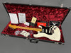 Vintage Fender Stratocaster electric guitar in white with maple neck and black pickguard in an open hard case lined with red velvet, including Fender certificate of authenticity, warranty card, strap, and accessories.