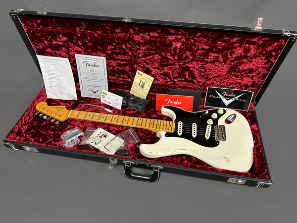 Vintage Fender Stratocaster electric guitar in white with maple neck and black pickguard in an open hard case lined with red velvet, including Fender certificate of authenticity, warranty card, strap, and accessories.