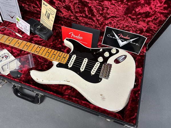Vintage white Fender Stratocaster electric guitar with black pickguard and maple neck in red plush-lined hard case with Fender paperwork and accessories