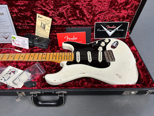 Fender Custom Shop vintage white Stratocaster electric guitar with maple neck and black pickguard in black hardshell case with red plush interior, including Fender warranty card, tremolo springs guide, black guitar strap, and extra pickup covers.