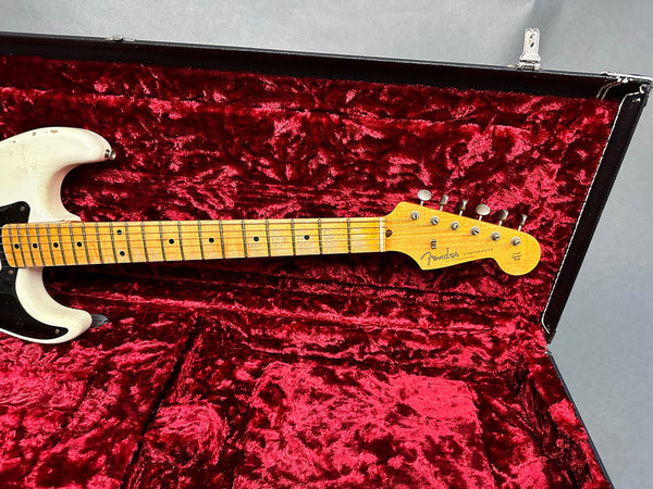 Vintage Fender Stratocaster electric guitar headstock and maple fretboard with black dot inlays inside a red velvet lined black hardshell case