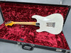 Vintage white electric guitar with maple neck and chrome hardware lying in open black hardshell case with plush red velvet interior