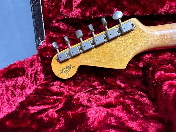 Vintage Fender guitar headstock with six tuning pegs in red velvet-lined guitar case