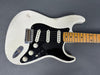 Vintage white electric guitar with black pickguard and maple neck showing wear and aged finish detail against gray background