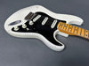 Vintage white electric guitar with black pickguard and maple neck showing wear and aging details on gray background