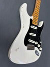 Close-up of vintage white electric guitar body with black pickguard, three single-coil pickups, maple neck, and visible wear and aging marks on the finish against gray background