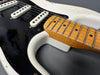 Close-up of vintage electric guitar neck and black pickguard showing maple fretboard and single coil pickups