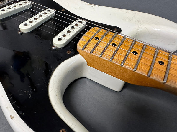Close-up of vintage electric guitar neck and black pickguard showing maple fretboard and single coil pickups