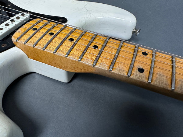 Close-up of electric guitar maple fretboard and white body with black pickguard showing aging and wear details