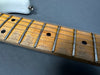 Close-up of a vintage electric guitar maple fretboard with metal frets and black dot inlays on gray background at Coffee House Guitars